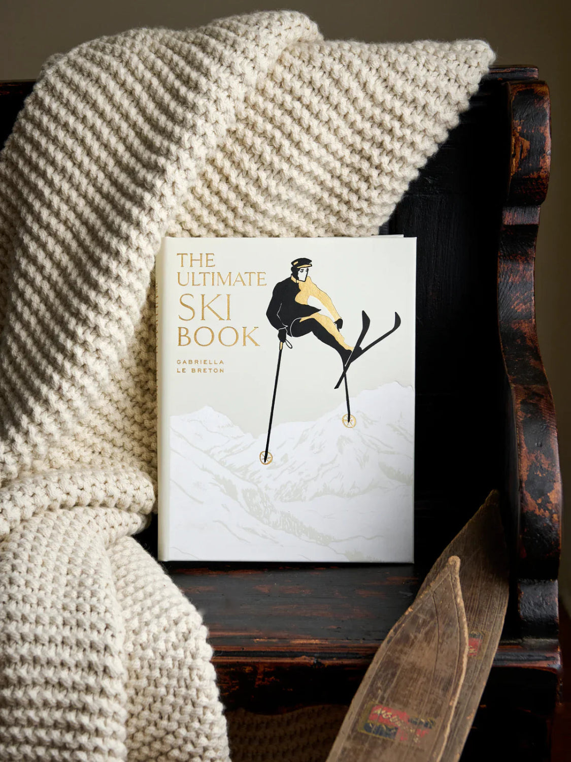 The Ultimate Ski Book on wooden bench with knit blanket