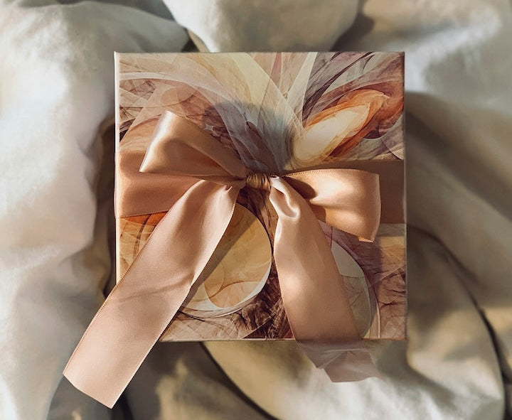 Aerial view of A blush-pink wrapped gift with bow layiag on a comforter