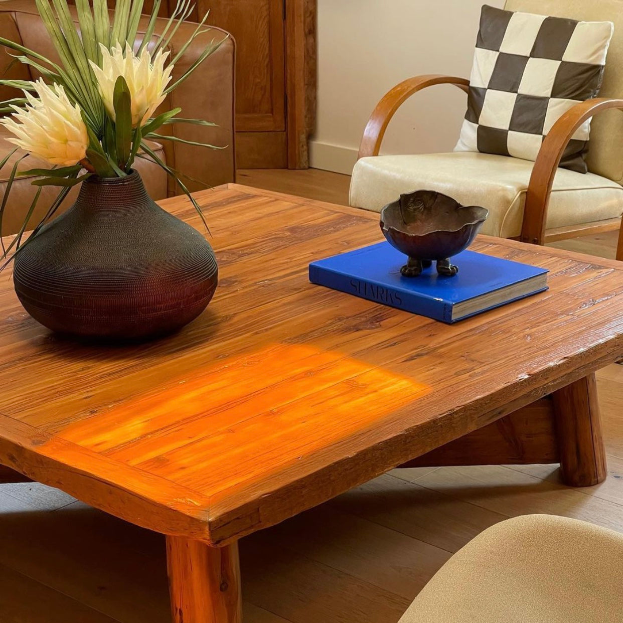 Wood coffee table with blue book and potted flowers