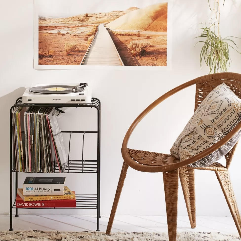 White turntable on side table with records, books, and next to a chair