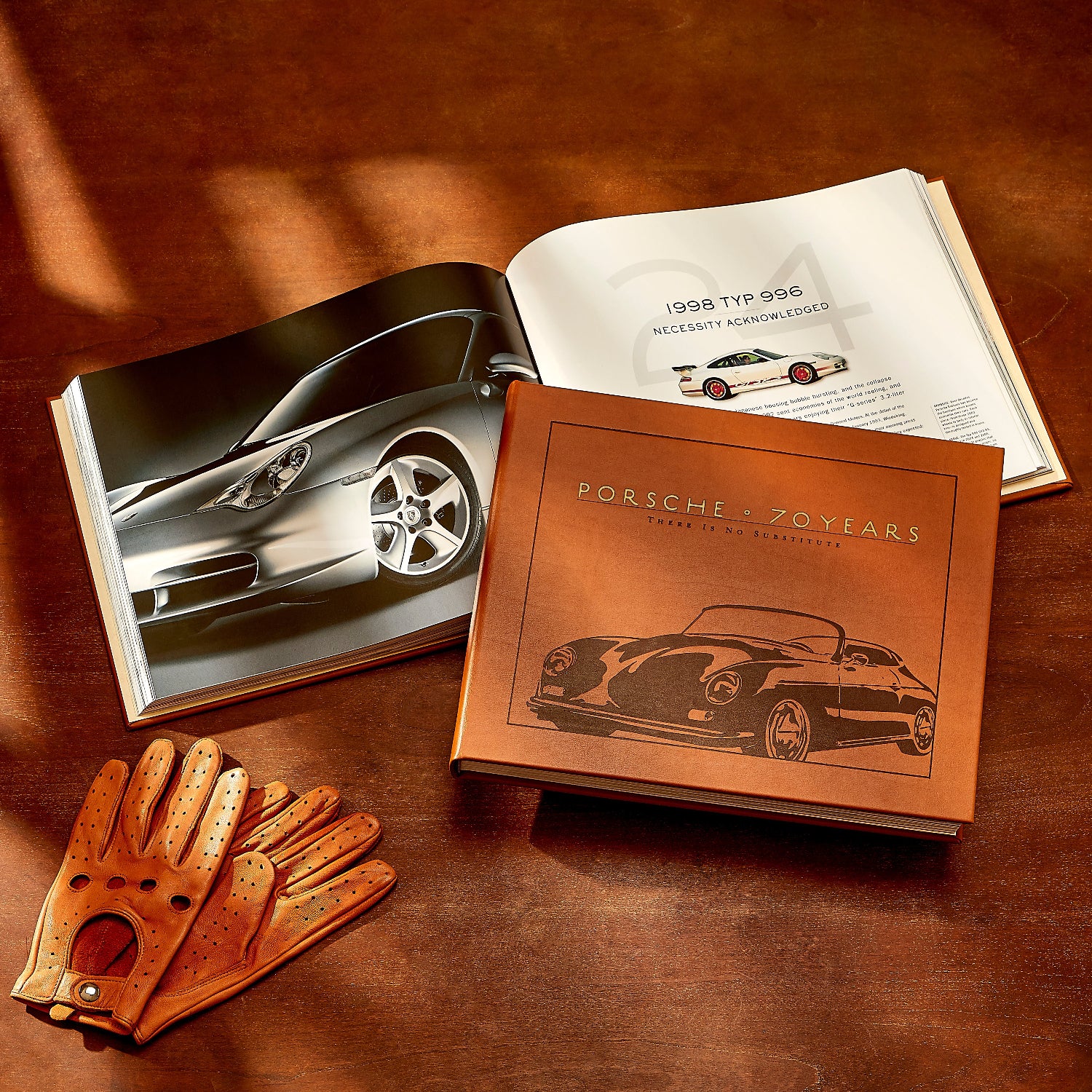 Porsche 70 Years book on wood table with driving gloves