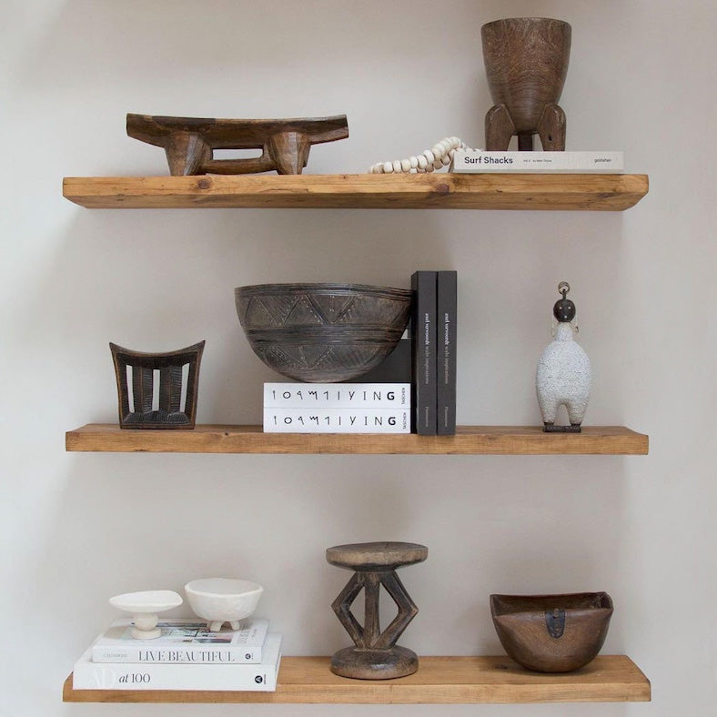 Wooden shelves with neutral tan decorative items against a white wall