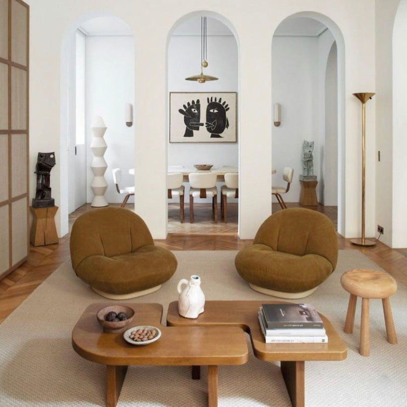 Modern tan living room with brown chairs, wooden coffee table, and abstract art on the wall.