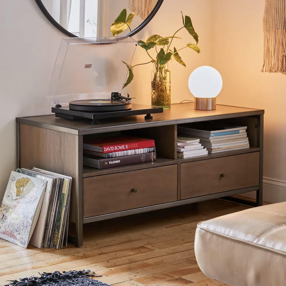 Wooden entertainment console with record player, books, and a lamp in a living room setting.